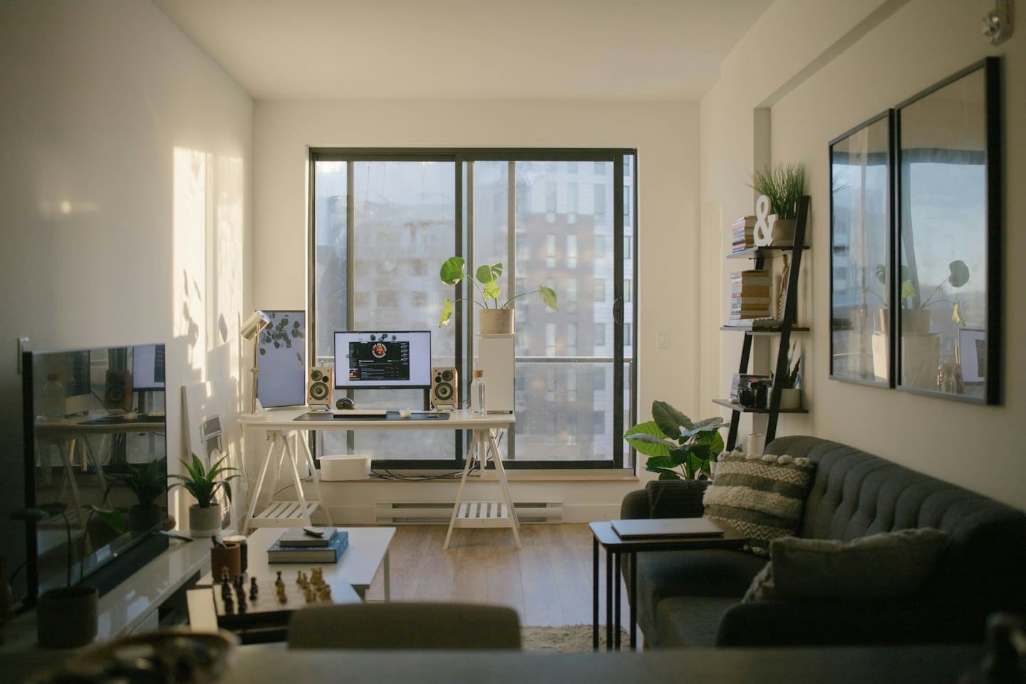 Home office in a bright living room with a desk and sofa.