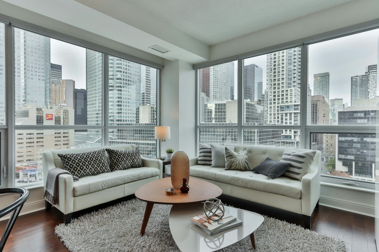 Modern living room with sofas, coffee tables, and cityscape view.