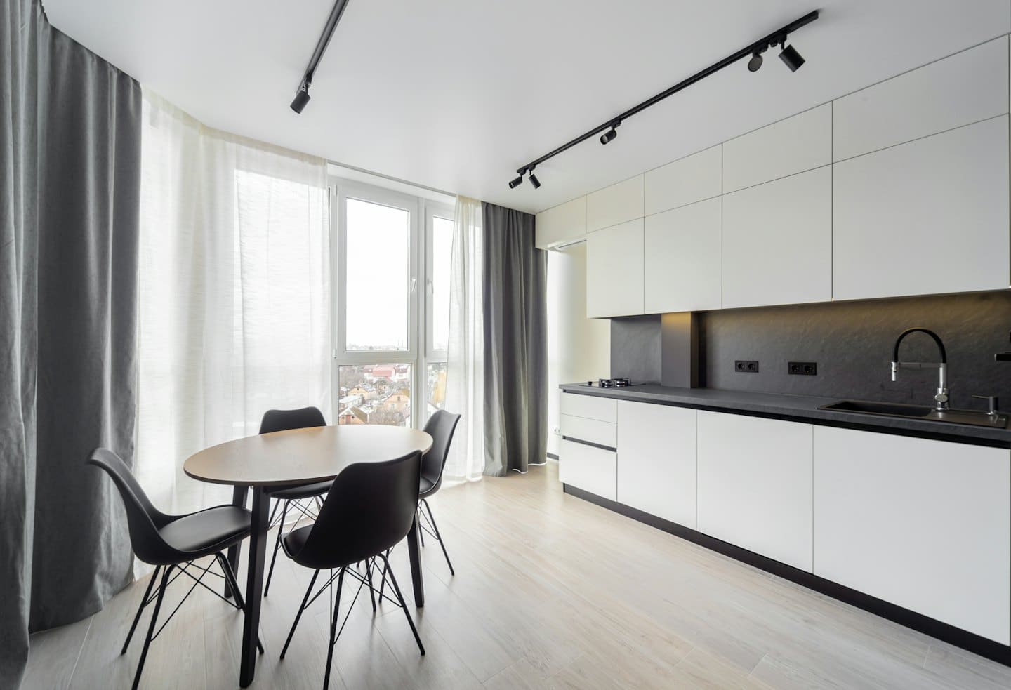 Modern apartment kitchen and dining area overlooking a cityscape.