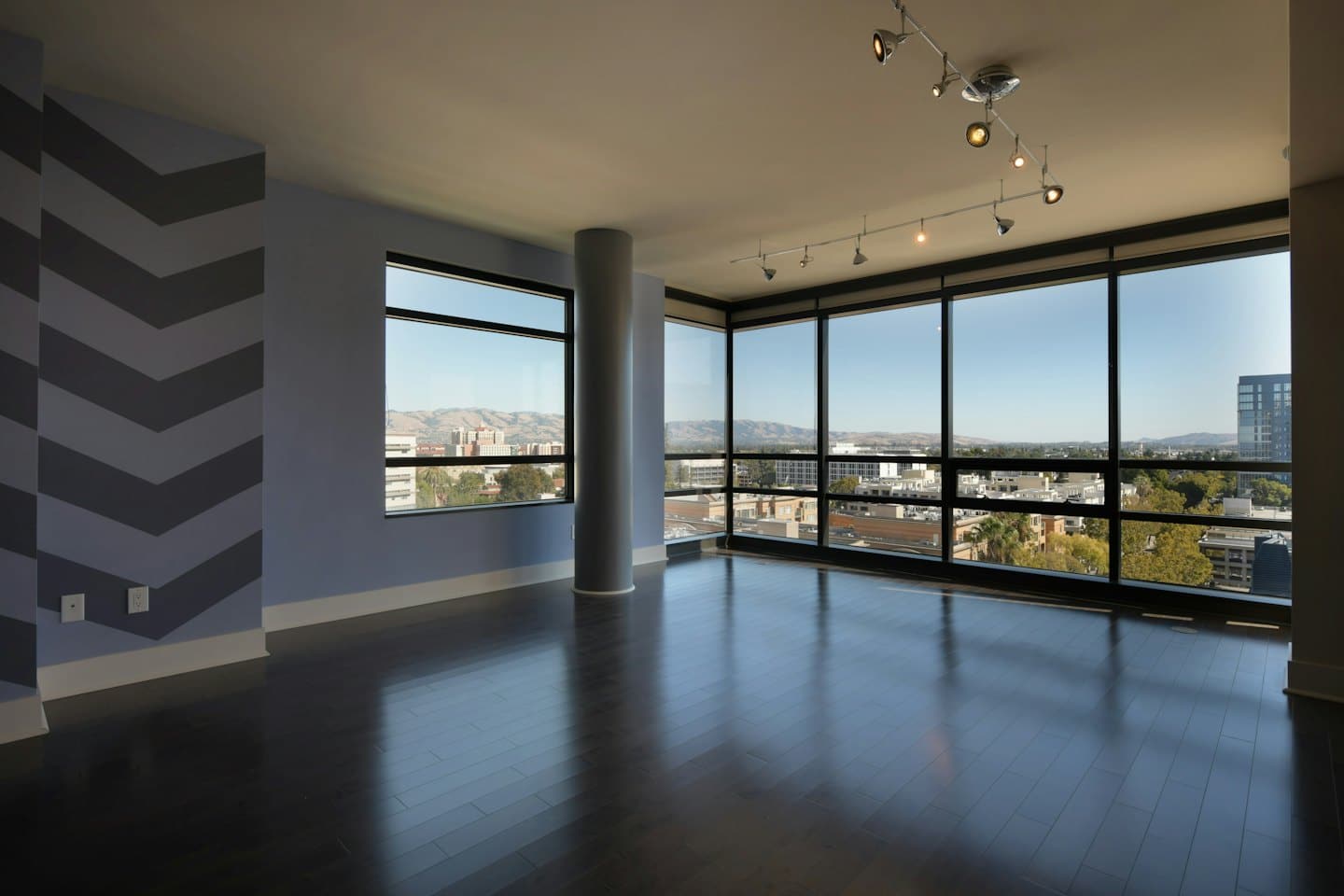 Modern apartment room with city view through large windows.